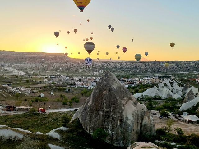 Hot air balloons floating over a landscape at sunrise or sunset.