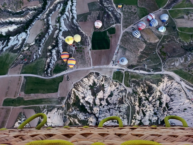 View from above of hot air balloons over a patchwork of fields.