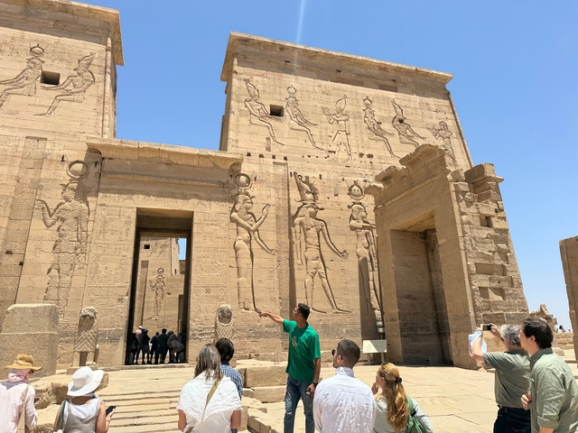 Tourists exploring ancient Egyptian ruins with a guide.