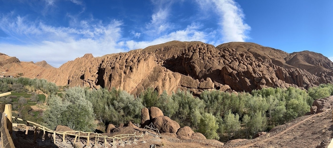 Rocky landscape with lush greenery under a bright blue sky.