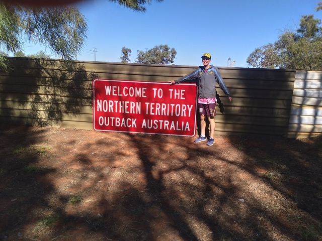       Person standing next to a Northern Territory sign.
  