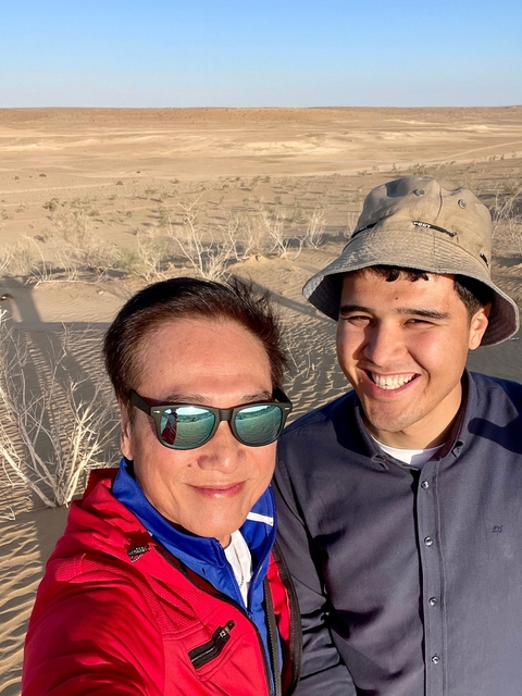 Two people smiling in a sunny desert setting.