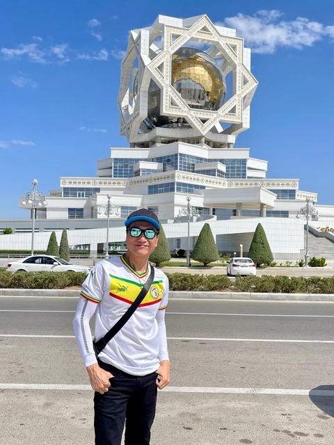       Person posing in front of a futuristic building in a city setting.
  