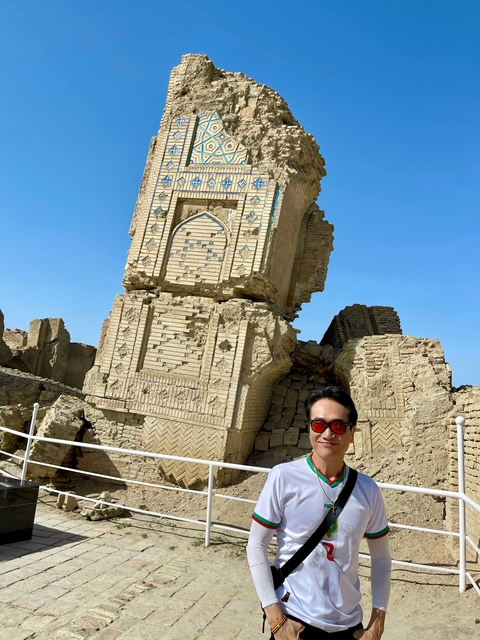       Person with ancient ruins in the background under a clear sky.
  