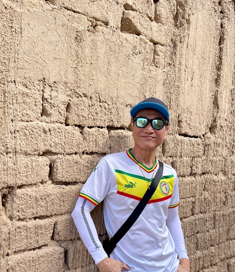 Person standing against a textured wall outdoors.