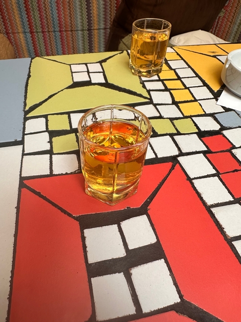 Glass of amber liquid on a colorful table.