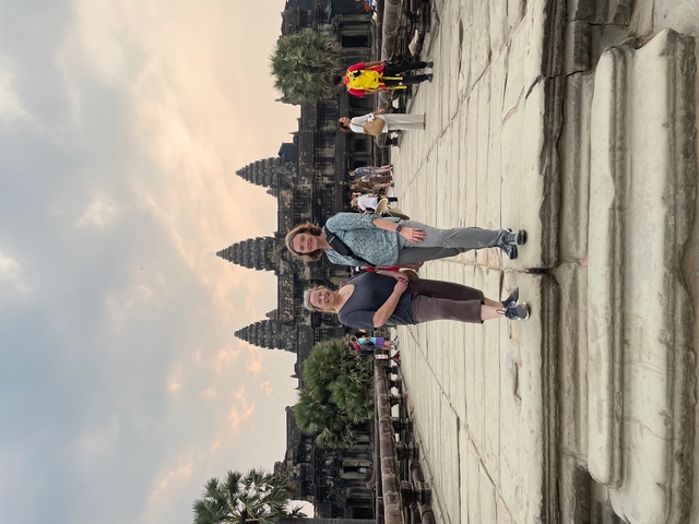Two people standing in front of Angkor Wat temple.