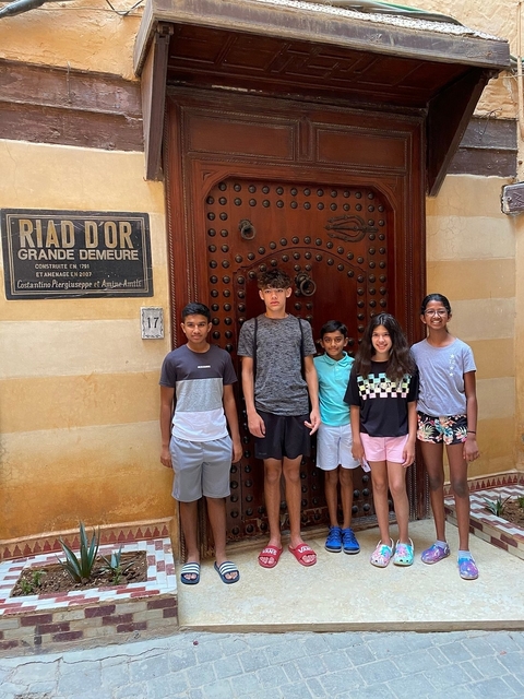 Group of children standing in front of an ornate door.