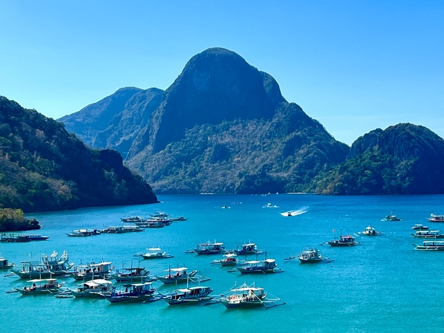      Seascape with traditional boats and rocky islands.
  