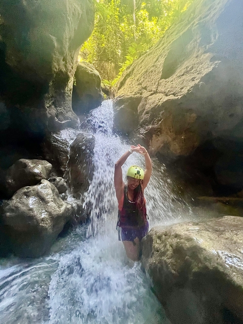       Person under a waterfall wearing a helmet and life vest.
  