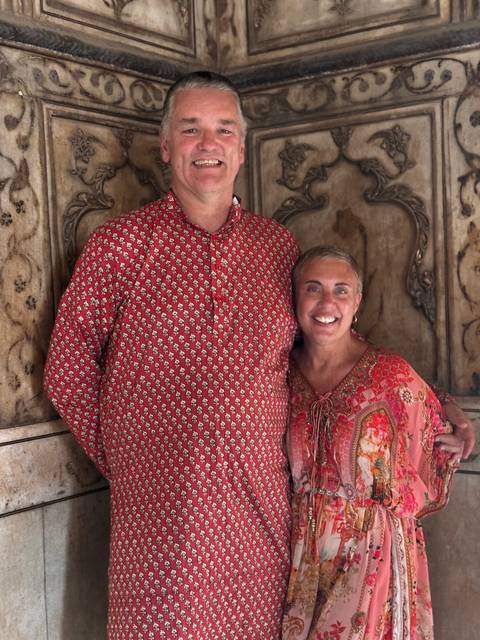       A couple standing with traditional clothing in an interior setting.
  