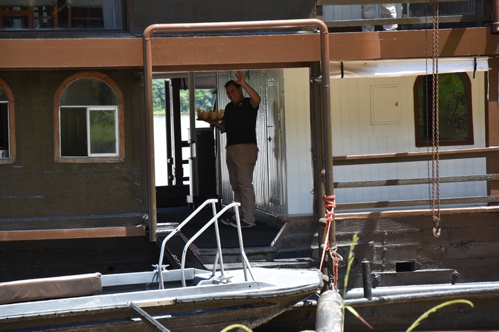 Person on the deck of a riverboat waving.