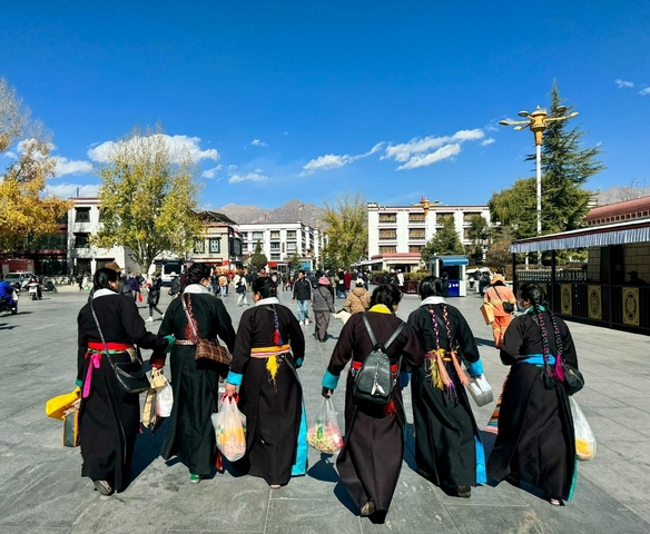 Traditionally dressed group walking through a town square.
