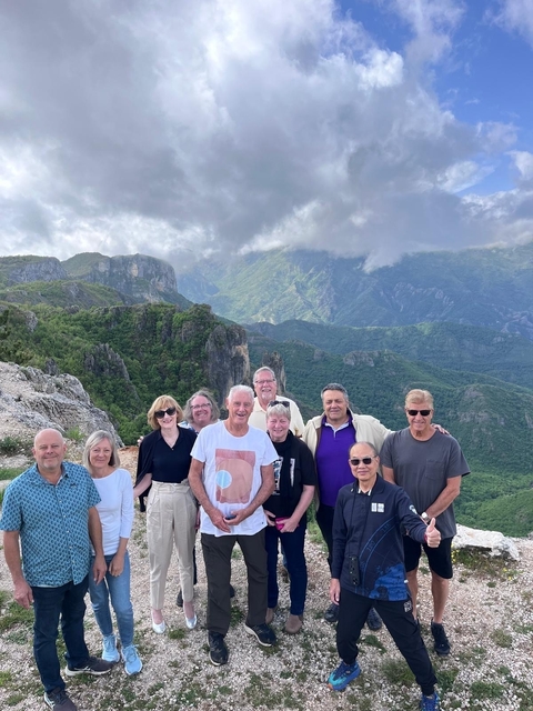 Group posing with mountains and clouds in the background.