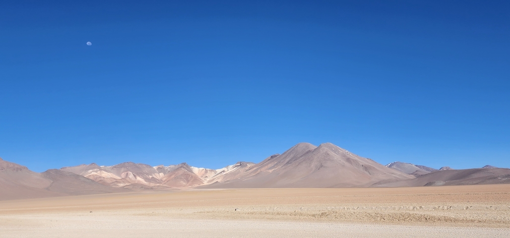       Expansive desert landscape with distant mountains and clear sky.
  