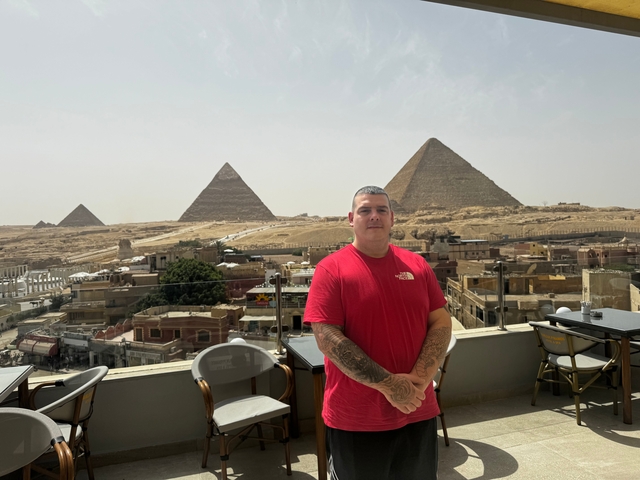 Man posing with pyramids in the background.