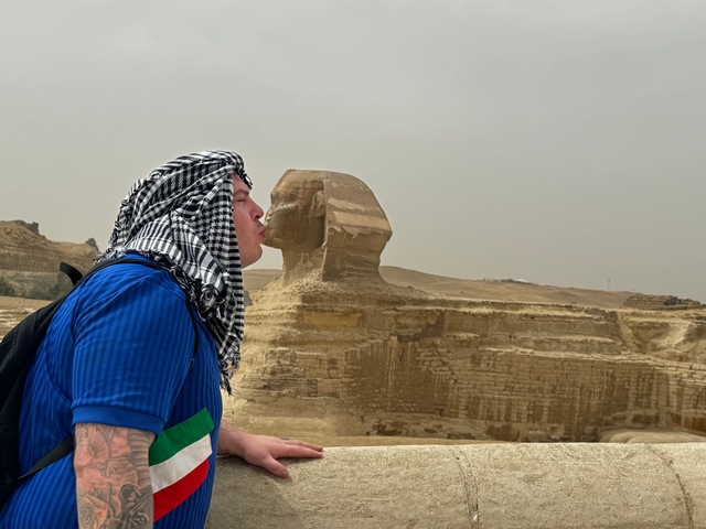 Man playfully posing in front of the Sphinx.