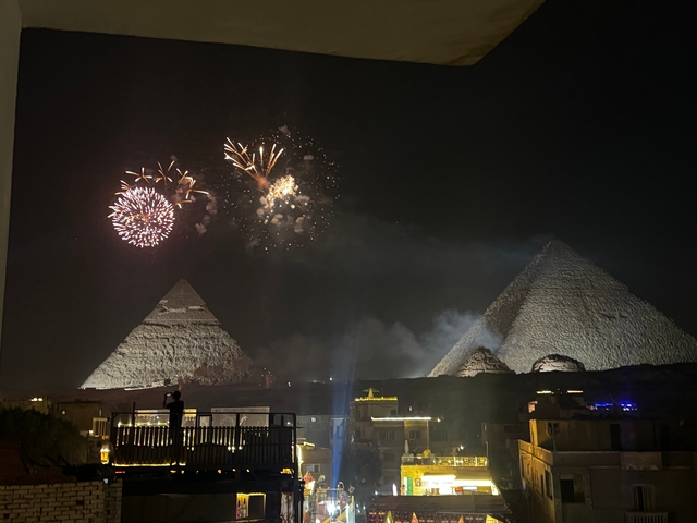 Fireworks lighting up the night sky above pyramids.