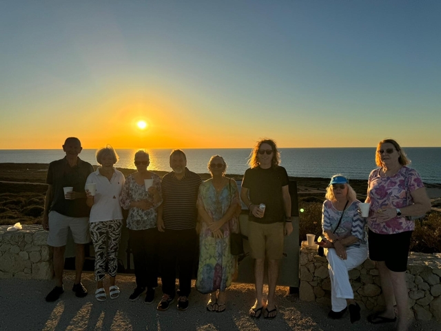 Group posing at sunset near the ocean.