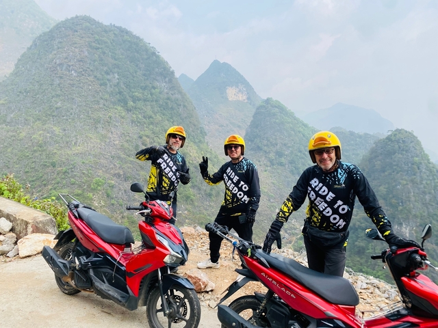 Three people on motorcycles with scenic mountain views.