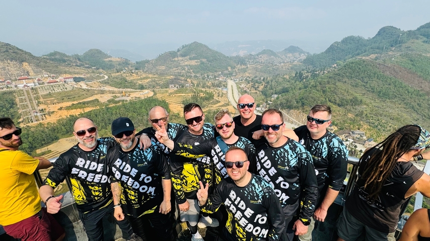 A group of people posing with a mountain landscape in the background.