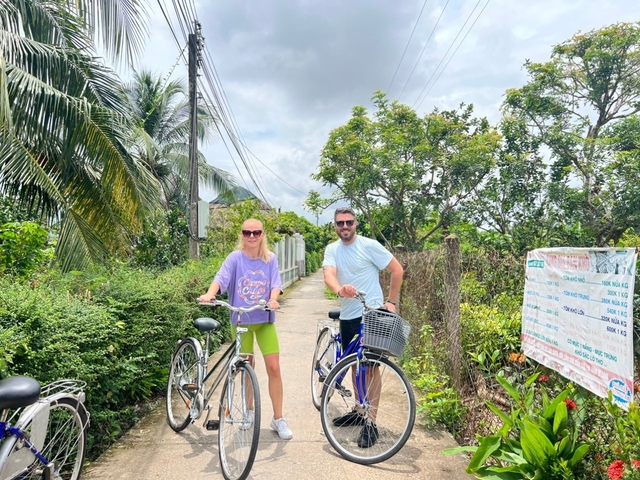Two people posing with bicycles on a rural path.
