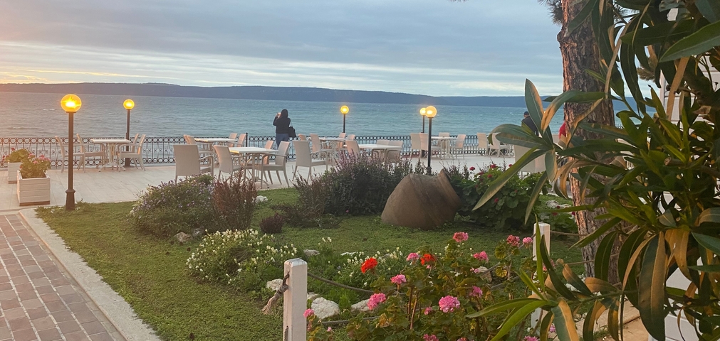 Seaside terrace with flowers and tables overlooking the water.