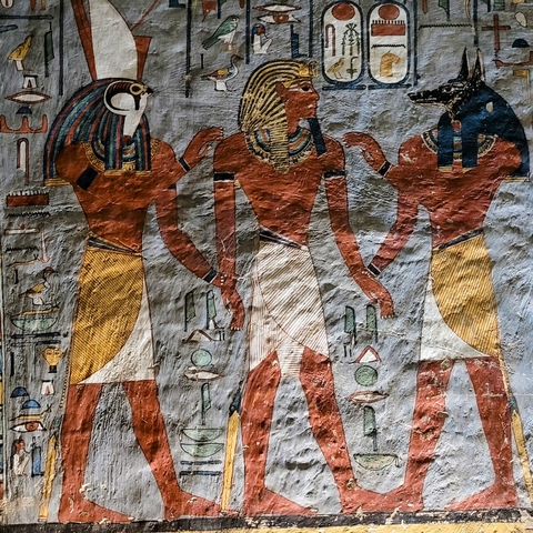 Colorful ancient Egyptian figures on a temple wall.