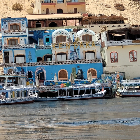       Colorful buildings and boats by the riverbank.
  