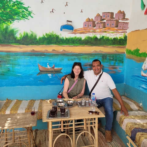 Tourists sitting in a shaded, painted outdoor setting.