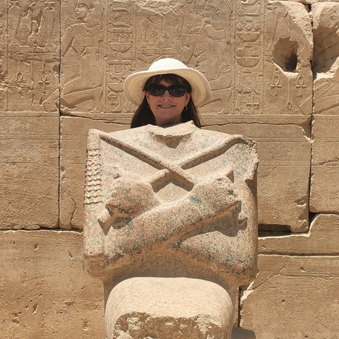 Tourist posing with ancient Egyptian statue.