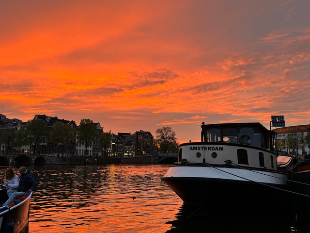       Boat docked at a canal during a stunning orange sunset.
  