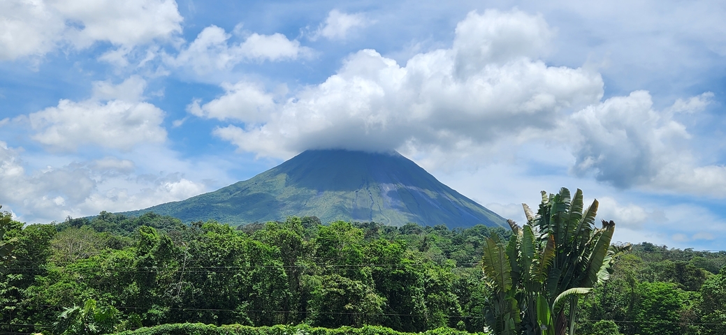 A picturesque view of Arenal Volcano with clouds partially covering its peak.
