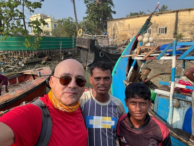 Three people posing with boats and water in the background.