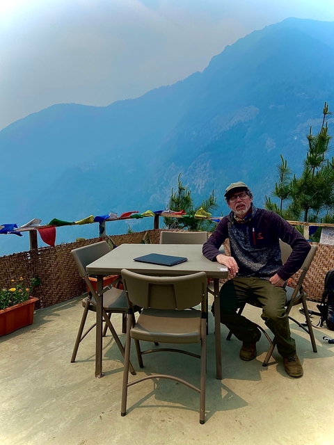 Person sitting in an outdoor area with a view of mountains.