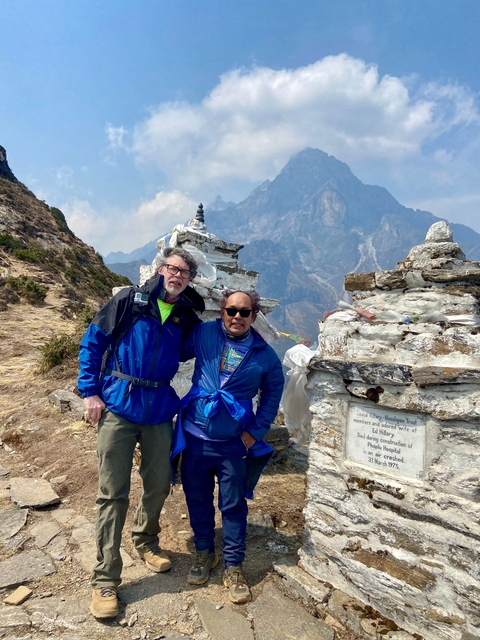 Two people with stone structures on a mountainous trail.