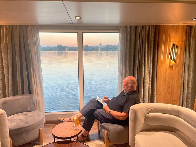 Man relaxing by a window with a view of a river.