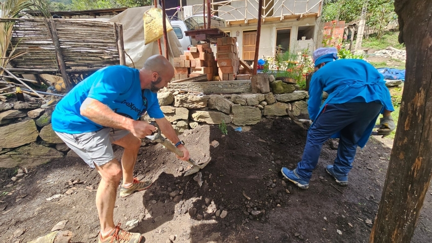 Two people working with soil and bricks outdoors.
