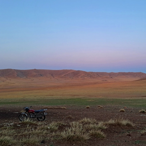 Expansive landscape with mountains and fields at dusk.