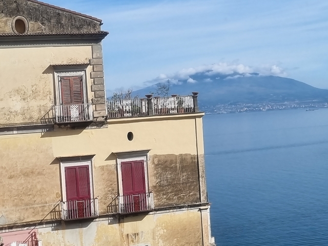 Old building with view of the sea and distant mountain.