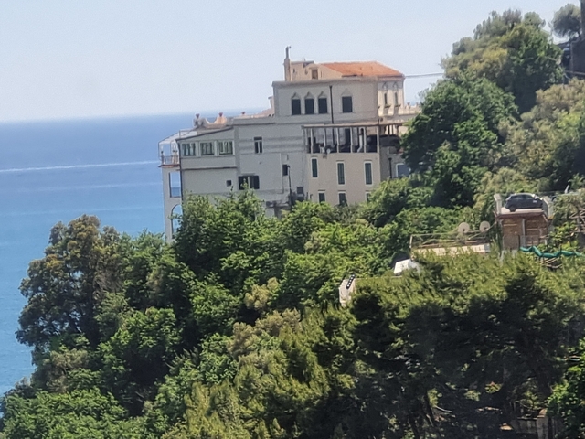 Building on a hill overlooking the blue sea.