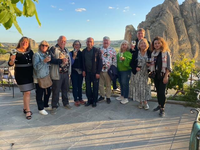Group of people posing with drinks in a scenic outdoor location.