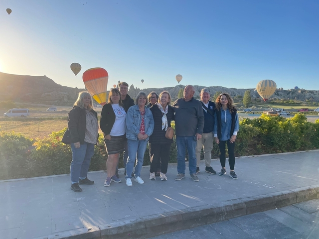       Group with hot air balloons floating in the background.
  