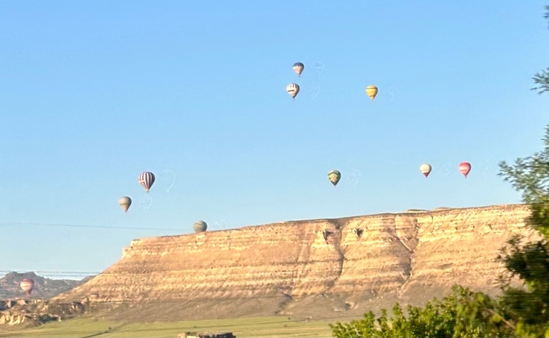       Hot air balloons ascending over a plateau.
  
