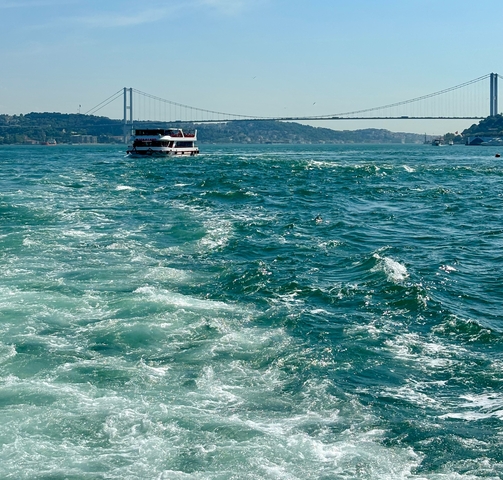       A boat on a large body of water with a bridge visible in the background.
  