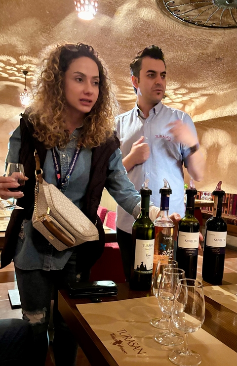       Two people sampling wines with several bottles on the table.
  