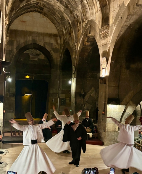       Whirling dervishes performing inside a historic building.
  