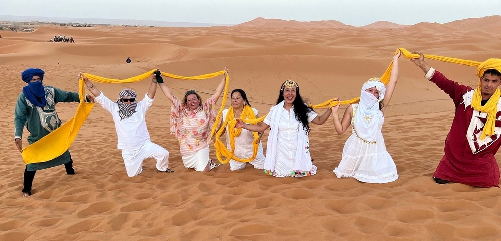       Group of people holding a yellow cloth in the desert.
  