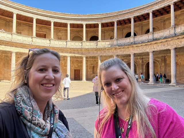 Two women smiling in a historical courtyard.