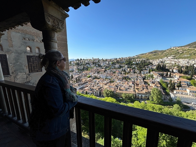       Woman gazing out over a scenic city view from a terrace.
  